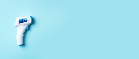 Digital medical infrared non contact thermometer gun for measuring temperature on blue background...