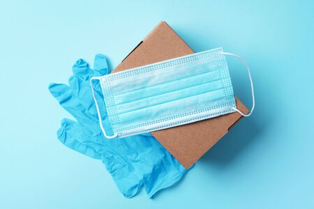 Craft paper cups, food box, gloves, bags, mask on blue background. Top view. Banner, copy space....
