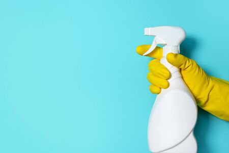 Hand in glove holding white plastic bottle of cleaning product, household chemicals. Copy space....