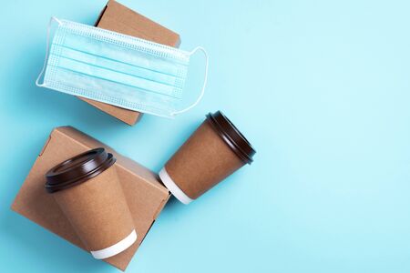 Craft paper cups with coffee to go and food box, lunch on blue background. Top view. Banner, copy space. Safe delivery, take away only concept. Food delivery service during coronavirus pandemic.の写真素材
