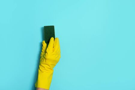 Hand in glove holding microfiber cleaning cloth, sponge on blue background. Copy space. Cleaning service concept. Spring general or regular clean up. Commercial cleaning company conceptの写真素材