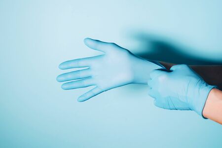 Woman doctor wears medical gloves over blue background. Copy space. National Doctors' Day....