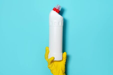 Hand in glove holding white plastic bottle of cleaning product, household chemicals. Copy space....