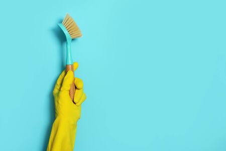 Hand in glove holding brush on blue background. Copy space. Cleaning house, cleaning toilet concept....