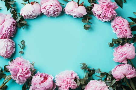 Frame pattern of pink peonies, eucalyptus flowers on pastel blue background. Flat lay, top view. Floral composition. Wedding, birthday, anniversary bouquet. Woman day, Mothers day. Creative floralの写真素材