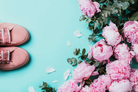 Pink sneakers, pastel pink peonies, eucalyptus flowers on pastel blue background. Flat lay, top view. Copy space. Floral composition. Wedding, birthday, anniversary bouquet. Woman day, Mothers day.の写真素材