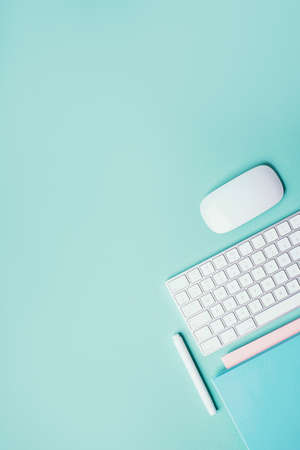 Home designer office workspace. White mouse, keyboard, notebook, pen on blue background. Top view. Copy space. Flat lay. Remote job, work. Feminine workspace. Blogger, business concept. Mock upの写真素材