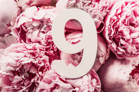 Creative layout. Pink peony flowers and digit nine 9. Birthday greeting card. Anniversary concept. Top view. Copy space. Stylish white numeral over flowers background. Numerical digit.の写真素材
