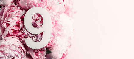 Creative layout. Pink peony flowers and digit nine 9. Birthday greeting card. Anniversary concept. Top view. Copy space. Stylish white numeral over flowers background. Numerical digit.の写真素材
