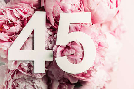 Peony flowers, digit forty-five. Birthday greeting card with inscription 45. Anniversary concept. Top view. White numeral on flower background. Numerical digit, Celebration event, template, flyerの写真素材