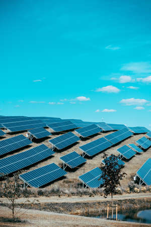 Solar panels against blue sunny sky produce green, environmentally friendly energy from sun. Blue...