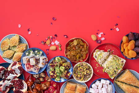 Middle Eastern sweets on red background. Arab dessert, baklava, halva, rahat lokum, sherbet, nuts, pistachios, dates, raisins, dried apricots, churchkhela, cookies. Top view. Flat lay. Copy spaceの写真素材
