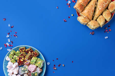 Middle Eastern sweets on blue background. Arab dessert, baklava, halva, rahat lokum, sherbet, nuts, pistachios, dates, raisins, dried apricots, churchkhela, cookies. Top view. Flat lay. Copy spaceの写真素材