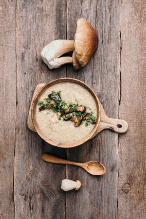 Homemade vegetarian mushroom soup with fried mushrooms, vegetables, spices, raw boletus edulis mushroom on wooden background. Top view. Copy space. Autumn harvest conceptの写真素材