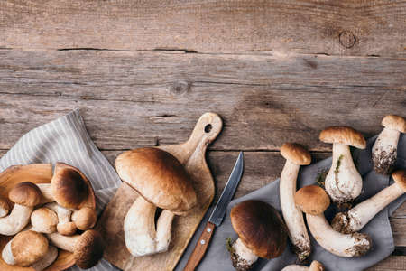 Fresh forest boletus mushrooms on wooden background. Top view. Copy space. Autumn harvest concept. Fresh picked Porcini mushrooms in basketの写真素材