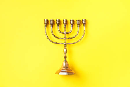 Golden hanukkah menorah on yellow background. Jewish holiday banner with copy space. Ancient ritual religious candle menorahの写真素材