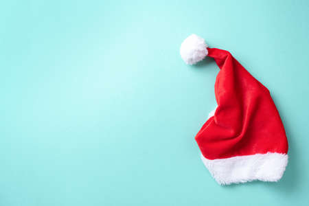 Red Santa Claus hat on blue background. Top view. Copy space. Advent time. New year composition. Decoration for winter holidays celebration. Christmas greeting cardの写真素材