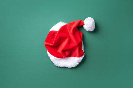 Red Santa Claus hat on green background. Top view. Copy space. Advent time. New year composition....