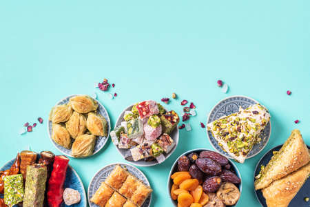Middle Eastern sweets on blue background. Arab dessert, baklava, halva, rahat lokum, sherbet, nuts, pistachios, dates, raisins, dried apricots, churchkhela, cookies. Top view. Flat lay. Copy spaceの写真素材