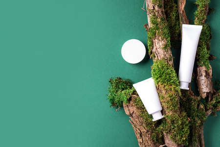 Cream jar, moisturizing lotion, shampoo or other cosmetic product in white blank bottle on green background with moss, tree bark. Skin care, organic body treatment, spa concept. Vegan eco friendlyの写真素材
