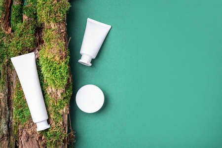 Cream jar, moisturizing lotion, shampoo or other cosmetic product in white blank bottle on green background with moss, tree bark. Skin care, organic body treatment, spa concept. Vegan eco friendlyの写真素材