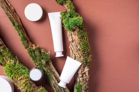 White unlabelled cosmetic bottle on brown background, natural moss over branches, bark. Skin care, organic body treatment, spa concept. Vegan eco friendly cosmetology product. Organic cosmetics.の写真素材