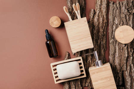 Bamboo bath accessories - soap dish, soap dispenser, tooth brush, organic dry shampoo for personal hygiene on wooden bark texture. Copy space. Top view. Zero waste, plastic free, sustainable conceptの写真素材