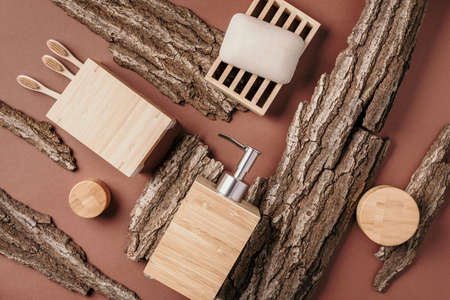 Bamboo bath accessories - soap dish, soap dispenser, tooth brush, organic dry shampoo for personal hygiene on wooden bark texture. Copy space. Top view. Zero waste, plastic free, sustainable conceptの写真素材