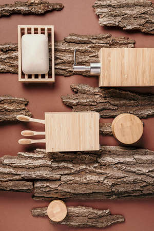 Zero waste, plastic free, sustainable concept. Bamboo bath accessories - soap dish, soap dispenser, tooth brush, organic dry shampoo for personal hygiene on wooden bark texture. Copy space. Top view.の写真素材