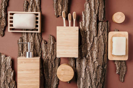 Bamboo bath accessories - soap dish, soap dispenser, tooth brush, organic dry shampoo for personal hygiene on wooden bark texture. Copy space. Top view. Zero waste, plastic free, sustainable conceptの写真素材