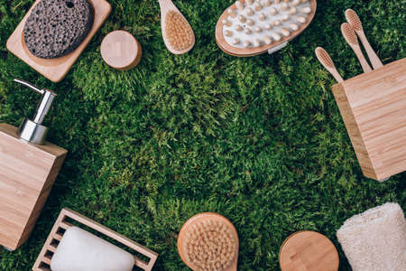 Zero waste, plastic free, sustainable concept. Bamboo bath accessories - soap dish, soap dispenser, tooth brush, organic dry shampoo for personal hygiene on green moss texture. Copy space. Top view.の写真素材