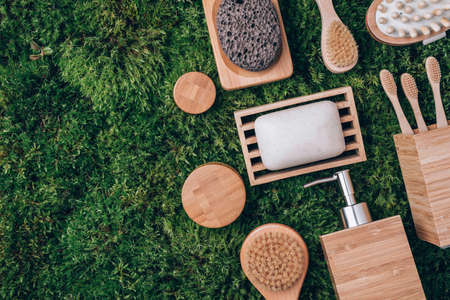 Wooden soap dish, shampoo, massage brushes, bamboo toothbrushes on green moss background. Zero waste, natural organic bathroom tools. Plastic free life. Ecological skin care, body treatment concept.の写真素材