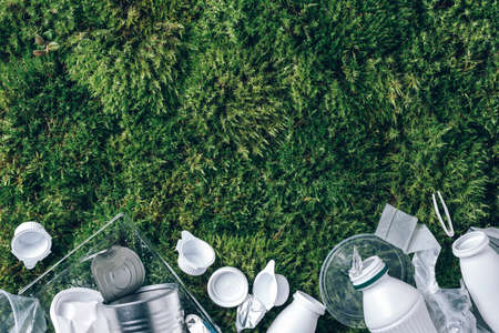 Food plastic packaging, trash on green moss background after picnic in forest. Top view. Copy space. Recycling plastic. Environmental pollution, ecology concept. Reuse garbage, recycle, plastic free.の写真素材