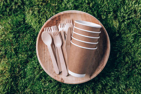 Eco craft paper tableware. Paper cups, dishes, bag, fast food containers and wooden cutlery on green moss background. Recycling or eco-friendly concept. Top view. Zero waste picnicの写真素材