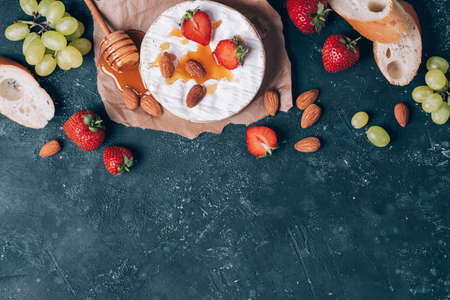 French camembert cheese served on grape, honey, almond, strawberries, baguette on dark background. Top view. Copy space. Romantic date night. Valentines Day, love concept. Romantic dinnerの写真素材