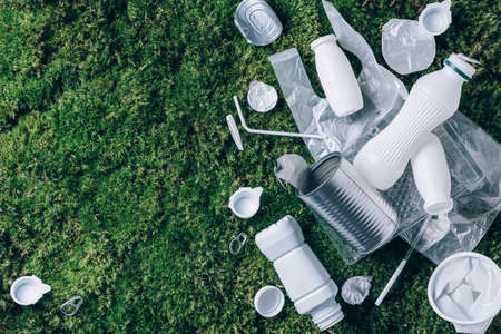 Plastic waste, food packaging, trash collection on green moss background after picnic in forest. Plastic free. Top view. Copy space. Recycling plastic. Environmental pollution, ecology concept.の写真素材