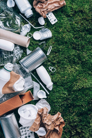 Food plastic packaging, trash on green moss background after picnic in forest. Top view. Copy space....