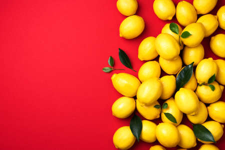 Lemons frame on red background. Immune system booster. Copy space. Top view. Flat lay. Citrus fruits. Vitamins for health. Liposomal vitamin C. Lemon for vegan, vegetarian alkaline dietの写真素材