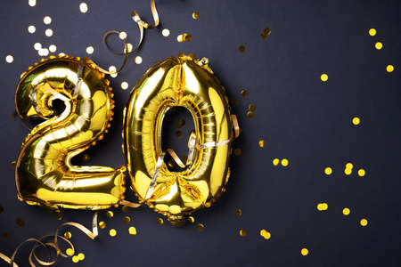 Gold foil balloon number, digit twenty. Birthday greeting card with inscription 20. Anniversary celebration event. Banner. Golden numeral, black background. Numerical digit, light bokeh, glitter.の写真素材