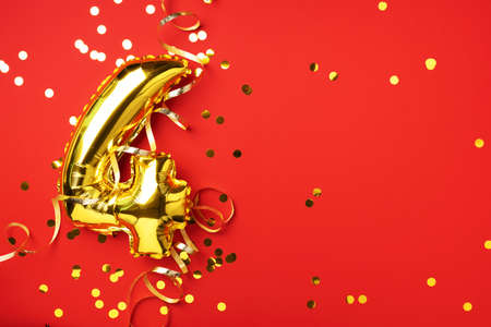 Gold foil balloon number and digit four 4. Birthday greeting card. Anniversary celebration event. Banner. Copy space. Stylish golden numeral, bright shiny glitter, red background. Numerical digit.の写真素材