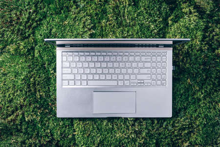 Laptop on green grass, moss background. Ecology travel, work outside office concept. Mindfulness, biophilic design, unplug concept. Digital detox. Summer office, work on vacation, freelance conceptの写真素材