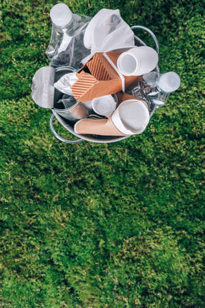 Plastic waste, food packaging in trash bin trash collection on green moss background after picnic in forest. Plastic free. Top view. Recycling plastic. Environmental pollution, ecology conceptの写真素材