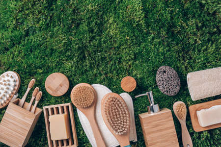Spa tools: cream, wooden brushes, soap dispenser, toothbrushes, bamboo massage brush on green grass,...