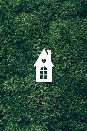 Eco house concept. Top view. White house model on green grass, forest moss background. Top view. Copy space. Eco friendly house. Zero waste, organic, sustainable lifestyle. Trendy eco home in natureの写真素材