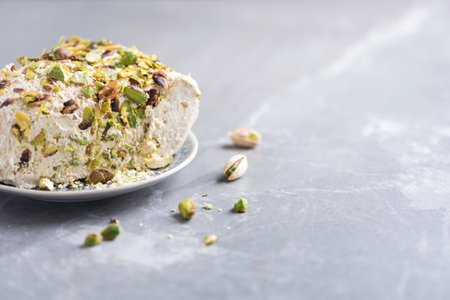 Sesame halva with pistachios on grey background. Top view. Copy space. Traditional middle eastern...