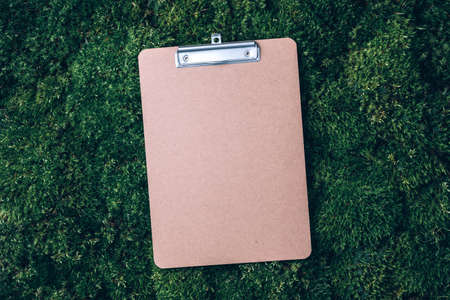 Top view of clipboard, paper, pen on green grass, moss background. Copy space. Flat lay. Office mock up, remote job. Wild nature, ecology concept. Sustainable, organic, zero waste lifestyleの写真素材