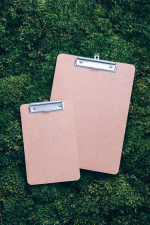 Top view of clipboard, paper, pen on green grass, moss background. Copy space. Flat lay. Office mock up, remote job. Wild nature, ecology concept. Sustainable, organic, zero waste lifestyleの写真素材