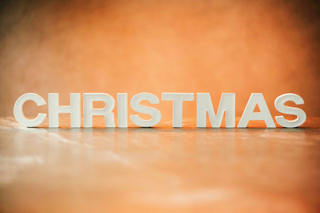 Word Christmas made of white concrete letters on orange light background. Copy space for your...