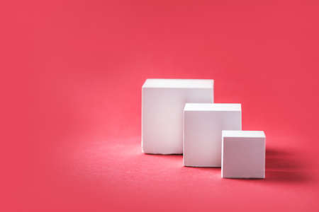 Abstract empty geometric shape podium for product on pastel red background. Copy space. White cube on pink backdrop. Pedestal template for advertising. Trendy minimal concept. Mock upの写真素材