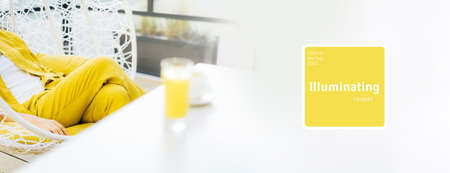 Trendy Illuminating and Ultimate gray duotone picture. Style girl with yellow clothes, glass of juice. Minimalistic style outdoor interior. Demonstrating trendy Color of the Year 2021. Bannerの写真素材